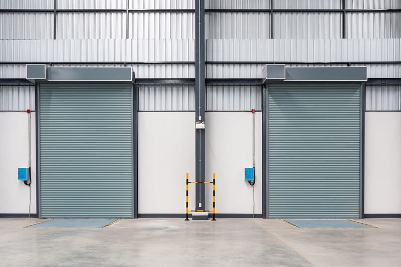 Two closed roller doors and concrete floors inside a factory
